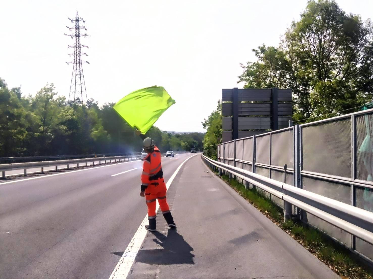 高速道路の現場で旗を掲げ、安全を支えるスタッフ